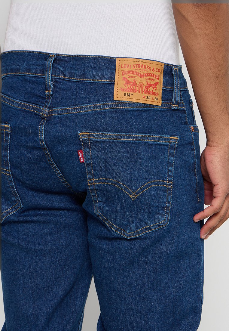 Blaue Jeans aus Denim mit geradem Schnitt. Verfügt über ein Lederpatch mit Markeninformationen und Steppnähten an den Taschen. Rotes Markenschild an der Gesäßtasche.
