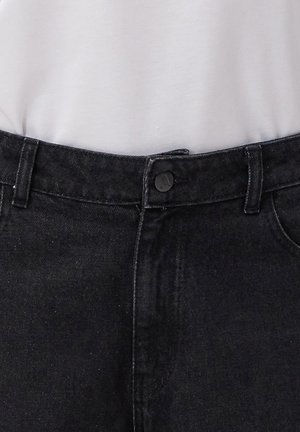 Czarne dżinsy o gładkiej fakturze, klasyczny pięciokieszeniowy krój oraz zapięcie na metalowy guzik. Pas wyposażony jest w szlufki na pasek.