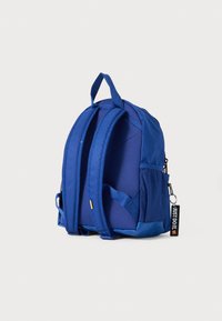 Sac à dos en tissu bleu avec une forme arrondie, des bretelles rembourrées, des poches latérales en mesh et un zip avec une étiquette "Just Do It".