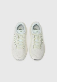 White mesh sneakers with light green accents. Features a textured upper, padded tongue, and lace-up design. Rounded toe and supportive sole.