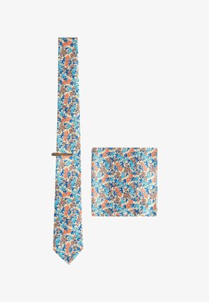 Floral necktie and matching pocket square with blue, orange, and brown flowers on a beige background, displayed on white surface.