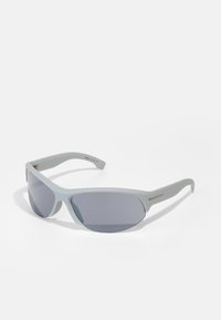 Gafas de sol grises con un diseño elegante y deportivo. Presentan lentes oscuros y un acabado mate en las monturas. Incluyen un sutil acento metálico en el lateral.