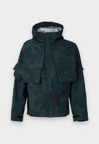 Camouflage-patterned jacket in dark green and black, features a hood, multiple front pockets, and adjustable cuffs. Fabric appears water-resistant.