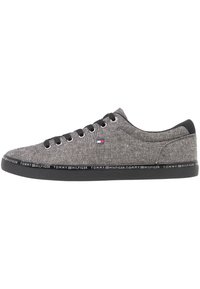 Sneaker grigio in tela con suola in gomma nera, dotato di occhielli argentati, lacci neri e striscia con logo lungo la suola.