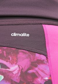 Primer plano de tejido deportivo morado y rosa con el logotipo "climalite" cosido cerca de la costura.