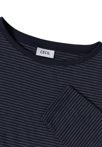 Chemise à rayures marines à manches longues avec un col rond et une petite poche poitrine. Le tissu semble doux avec une texture lisse. Étiquette "Cecil" visible.