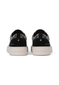 Sorte og grå mønstrede sneakers med ruskindsdetaljer, en beige gummisål og et logo på hælen. Rundet form med lav skæring.