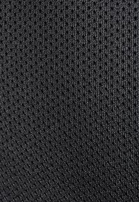 Tissu en maille noire présentant un motif texturé cohérent de petits trous espacés uniformément, offrant respirabilité et flexibilité.