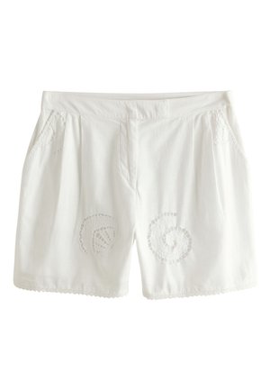 Białe damskie szorty z koronkową lamówką na brzegach, z dekoracyjnymi wycięciami w kształcie muszelek z przodu oraz plisowanymi kieszeniami po bokach.