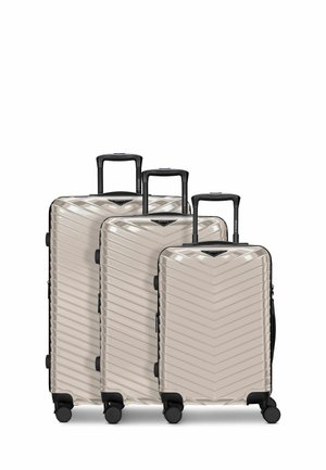 Drei beige Hartschalenkoffer mit schwarzen ausziehbaren Griffen und vier Rollen, vom größten bis zum kleinsten angeordnet.