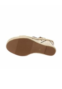 Sandalo espadrille con tomaia in tessuto intrecciato beige e nero. Presenta una suola in gomma con scanalature per una migliore aderenza. Design piatto.