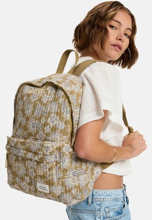 Sac à dos matelassé à motifs floraux dans des tons dorés et bleus doux, avec une poche avant et des bretelles rembourrées pour plus de confort. Logo de la marque affiché.