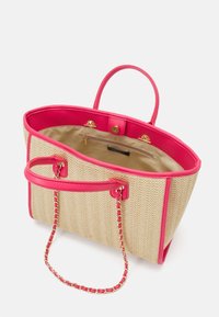 Torebka z plecionej słomy z różowymi syntetycznymi wykończeniami i uchwytami. Wnętrze z złotą podszewką i dodatkową kieszenią na zamek do przechowywania.