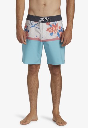 Bañador de hombre con una sección inferior azul y un estampado floral en rosa, rojo y azul en la parte superior. El material es ligero y de secado rápido.