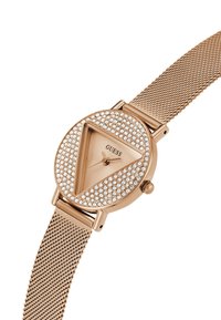Orologio in oro rosa con quadrante triangolare, circondato da cristalli trasparenti, e cinturino a rete. Presenta lancette delle ore e dei minuti minimaliste.