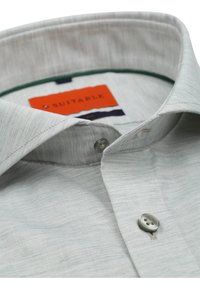 Lichtgrijs shirt met korte mouwen, voorzien van een subtiele textuur, met een geknoopte kraag en plastic knopen. Het label toont het "Suitable" merk in het oranje.