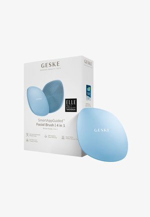 Brosse faciale en silicone bleu avec une forme ergonomique, surface texturée pour le nettoyage, et un emballage présentant les détails du produit et les logos.