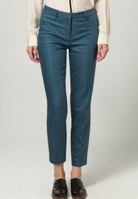 Teal op maat gemaakte broeken met een gladde textuur, slanke pasvorm en persplooien, gecombineerd met zwarte gepolijste veterschoenen.