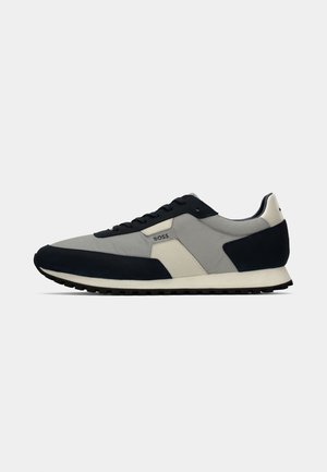 Sneakers with a mix of grey and navy suede and fabric. Features a white sole and black laces, with a logo on the outer side.
