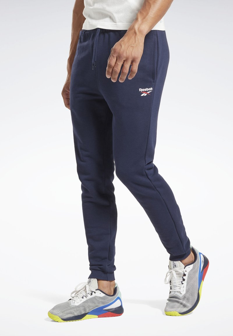 Marineblå sweatpants med en slim fit, snoretræk i taljen og Reebok-logo på låret; parret med multicolor sportssko.