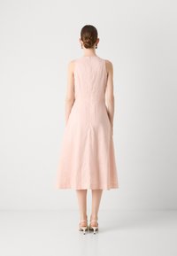 Lys rosa ermeløs kjole med en tettsittende liv og flytende A-line skjørt. Har en glidelås bak. Glatt, lett stoff.