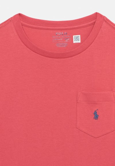 Κόκκινη μπλούζα με στρογγυλή λαιμόκοψη και μικρή τσέπη στο στήθος, με μπλε κεντημένο λογότυπο παίκτη πόλο και τυπωμένη εσωτερική ετικέτα με το εμπορικό σήμα και το μέγεθος.