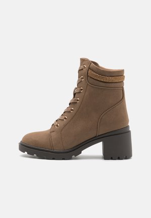 Bottines marron avec une surface texturée, un laçage à l'avant et des accents dorés décoratifs autour du col. Talon épais noir avec une semelle robuste.