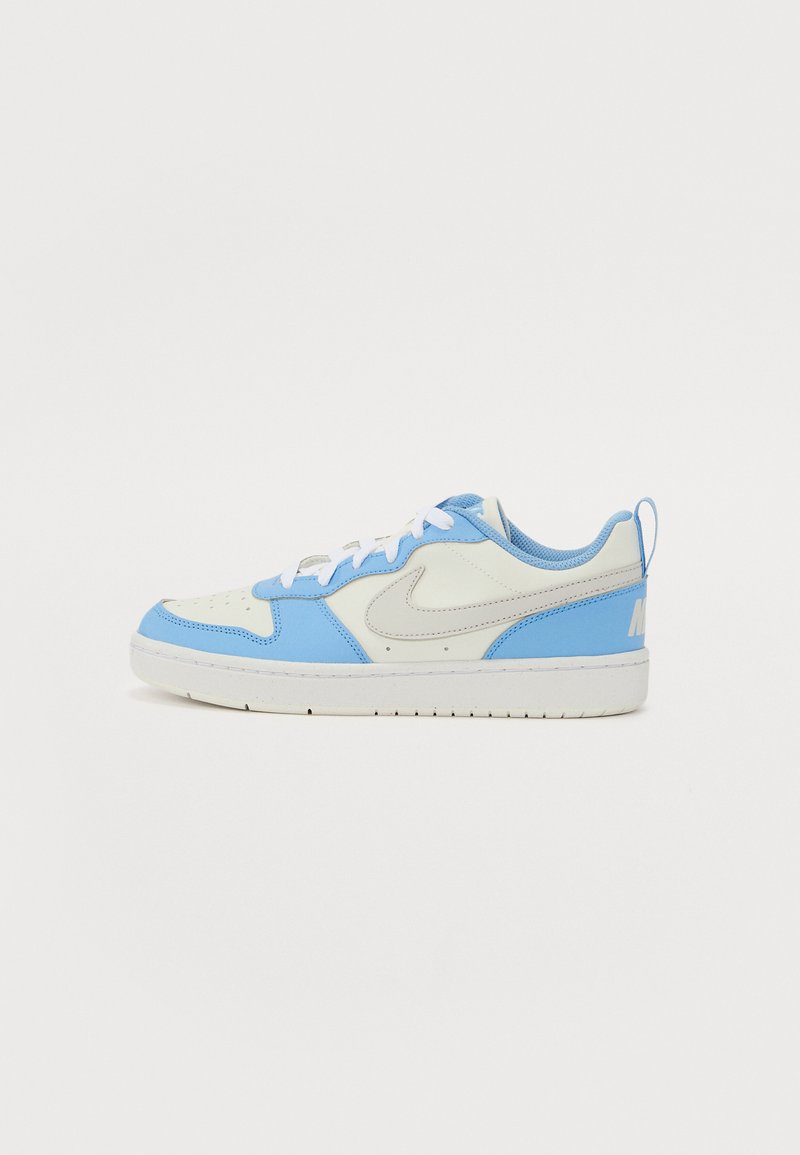 Sneaker bleu clair et crème avec des lacets blancs, détail perforé au niveau des orteils et semelle texturée. Présente un logo gris sur le côté.