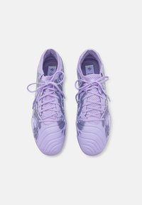 Purple athletic shoes with a mesh upper, tonal laces, and shiny accents. Features a textured sole design and a label on the tongue.