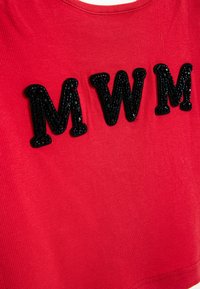 Top de tejido de rayas rojas con grandes letras negras de lentejuelas "MWM" exhibidas de manera prominente en la parte delantera.