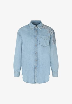 Camicia di jeans azzurri chiaro con bottoni sul davanti, maniche lunghe, una tasca sul petto e decorazioni floreali su una spalla.
