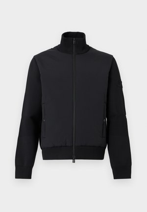 Schwarze Herrenjacke mit Reißverschluss, geripptem Stehkragen, gerippten Bündchen, gepolstertem Vorderteil und seitlichen Taschen mit Druckknopfverschluss.