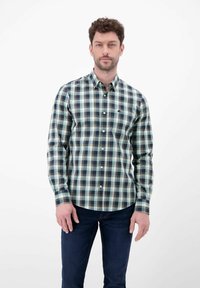 Skjorte med tern i marineblå, grøn og hvid. Har lange ærmer, krave og knapper foran. Bæres med mørke jeans.