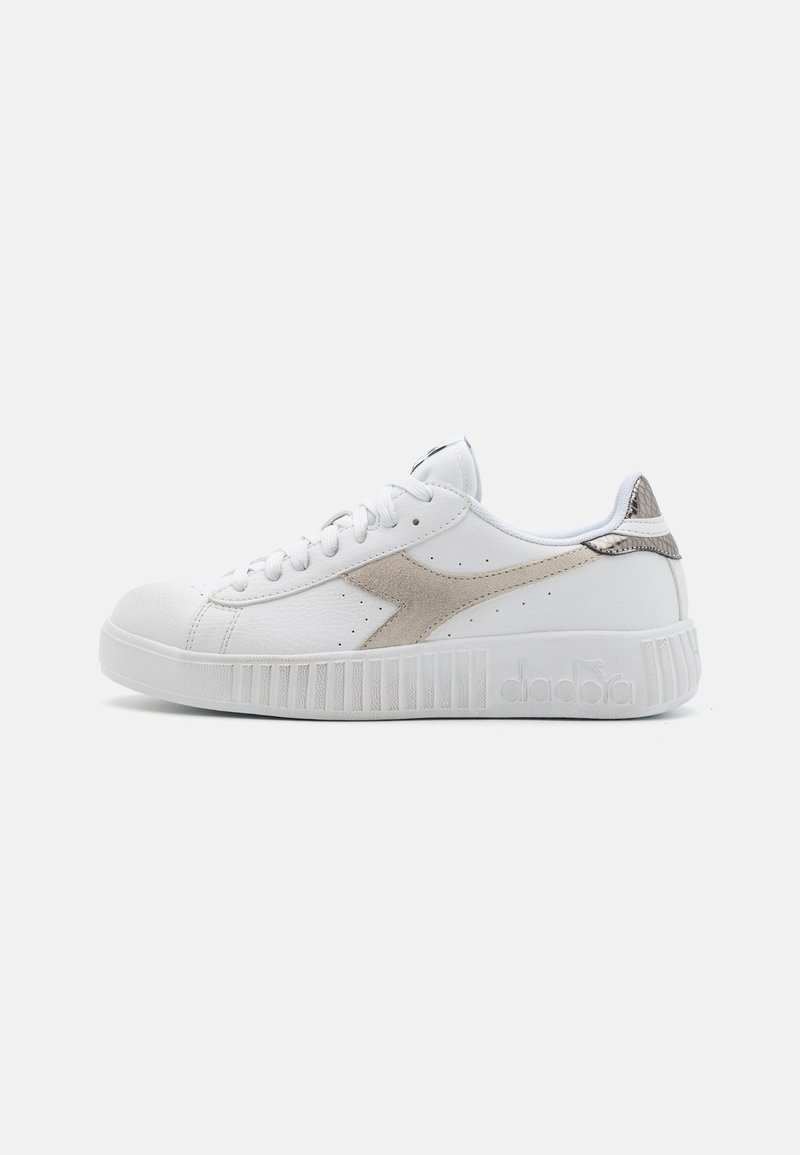 Baskets blanches en cuir, avec un accent beige et un talon texturé, dotées d'une semelle en caoutchouc striée et de détails perforés sur le dessus.