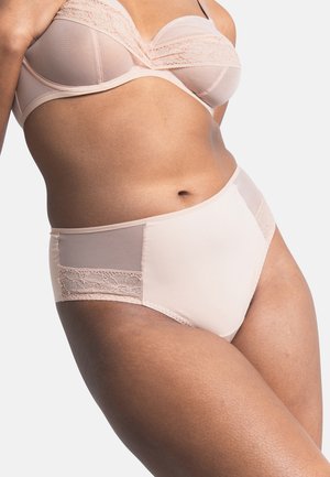 Vrouw draagt een licht perzikkleurige beha met kanten afwerking en bijpassende slip met hoge taille, zichtbaar van midden torso tot aan de bovenbenen.