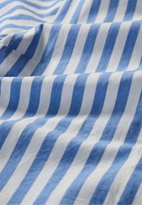 Tessuto a righe blu e bianche con strisce alternate larghe e strette, caratterizzato da un aspetto morbido e testurizzato tipico del cotone leggero.