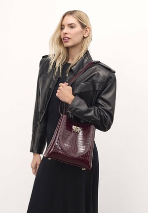 Burgunderfarbenes Handtasche aus Krokolederprägung mit strukturierter Form, glänzender Oberfläche, Obergriff und metallischen Akzenten.