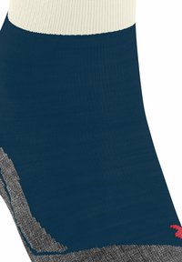 Calza corta con corpo blu navy, profilo a coste color crema e motivo grigio testurizzato in basso sui lati. Piccolo logo rosso sulla caviglia esterna.