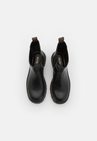 Black leather ankle boots with rounded toes, elastic side panels, and pull tabs. Features a thick black sole with visible stitching.