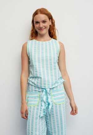 Top sin mangas azul claro y pantalones a juego con rayas blancas verticales. Los pantalones tienen dos bolsillos laterales con detalles en verde neón. Tela texturizada.