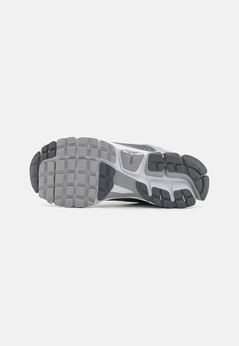 Suela de zapato con un diseño de goma texturizada, que presenta una combinación de colores negro y gris, surcos profundos y una sección angular para mayor estabilidad.
