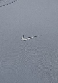 Hall hall Nike t-särk, millel on väike musta värvi tikitud logo, valmistatud siledast kangast puhta ja minimalistliku disainiga.
