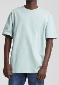 T-shirt en coton bleu clair avec des manches courtes, un col ras du cou et une coupe décontractée. Texture lisse, sans motifs ni embellissements visibles.