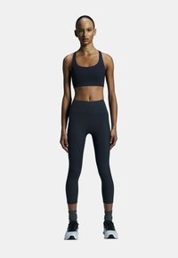 Zwarte sport-bh en high-waisted leggings van rekbare stof; aansluitend ontwerp met een gladde textuur, strakke lijnen en minimale branding.