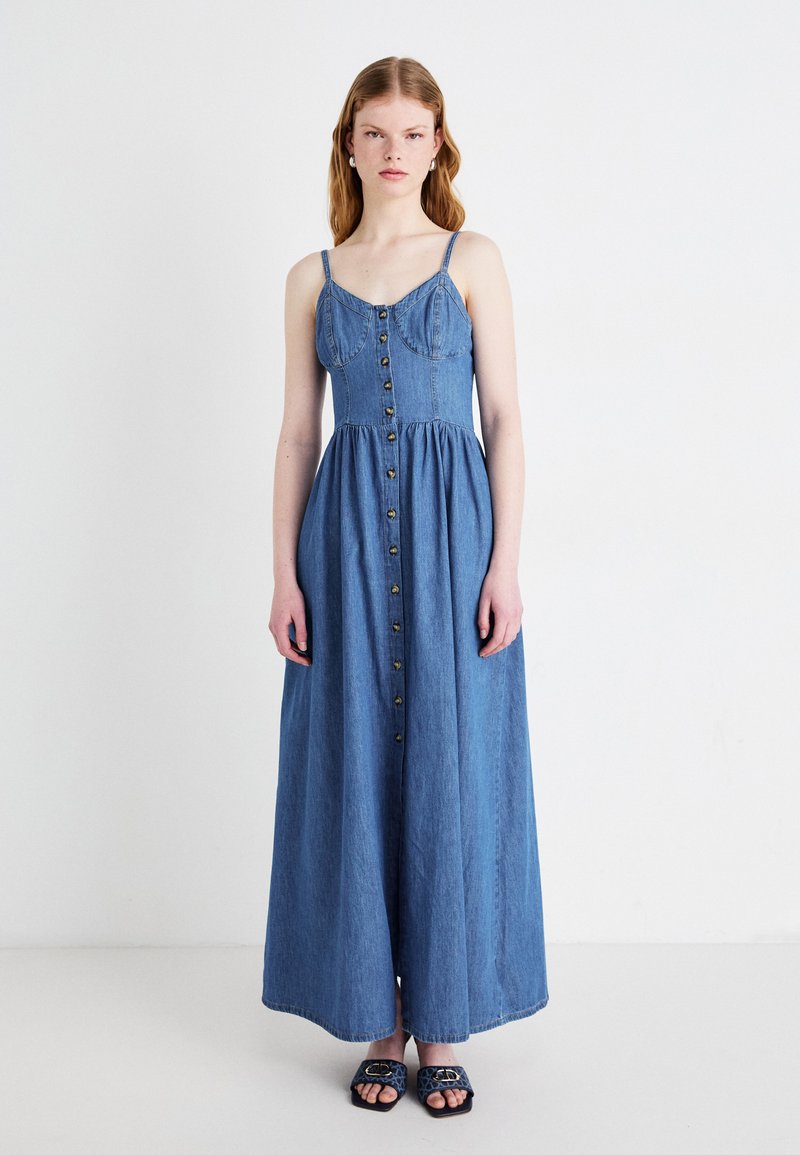Denim maxikjole med tynne stropper, knappelukking foran, tettsittende bodice og utsvingt skjørt. Lys blå farge, glatt tekstur, uformelt design.