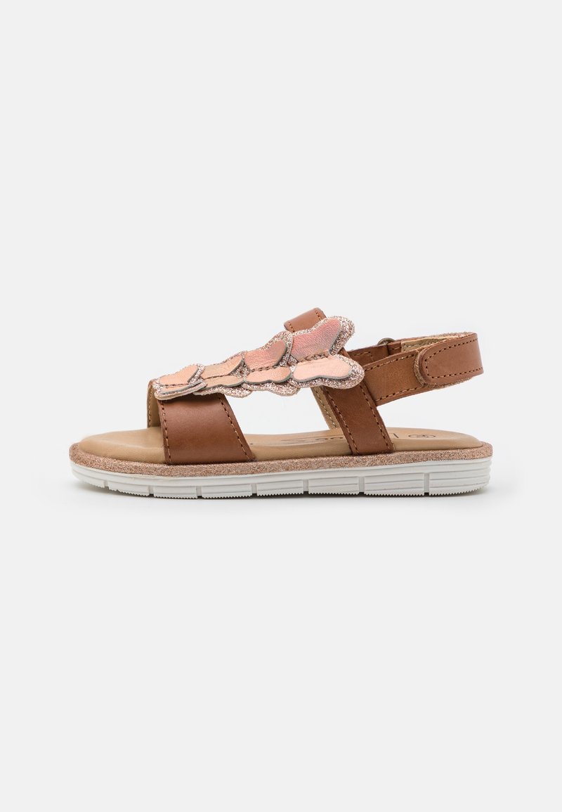Brown leather sandal with pink scalloped accents, adjustable strap, and white rubber sole, featuring a flat and textured footbed.