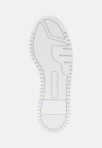 Suola di scarpa in gomma bianca con motivi di grip testurizzati, un logo centrale e un design liscio e curvo. Arricchita da scanalature per flessibilità.