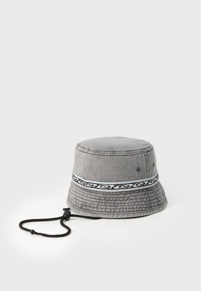 Grå bøttehatt laget av denim med en teksturert overflate. Har et mønstret bånd rundt kronen og en svart justerbar snor.