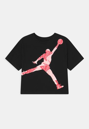 Camiseta negra con una silueta de patrón geométrico en rojo y rosa de un jugador de baloncesto saltando y alcanzando una pelota.