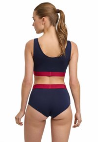 Bra in cotone blu navy e slip a vita alta abbinati con un elastico rosso a contrasto. Tessuto liscio, taglio contemporaneo, design minimalista.